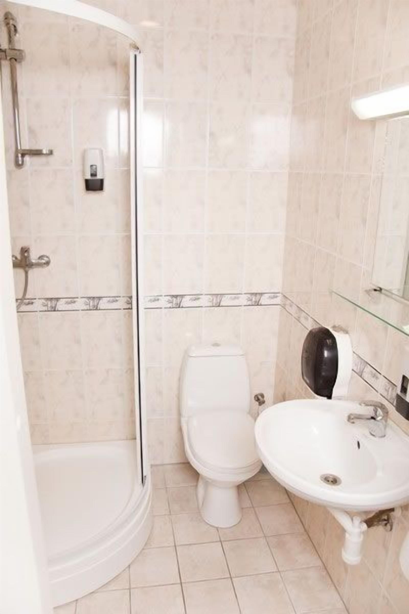 A bathroom with a glass shower enclosure, a toilet, and a sink.