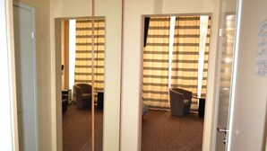 Een hotelkamer met vloerbedekking, een stoel, een bureau en een raam met gestreepte gordijnen.