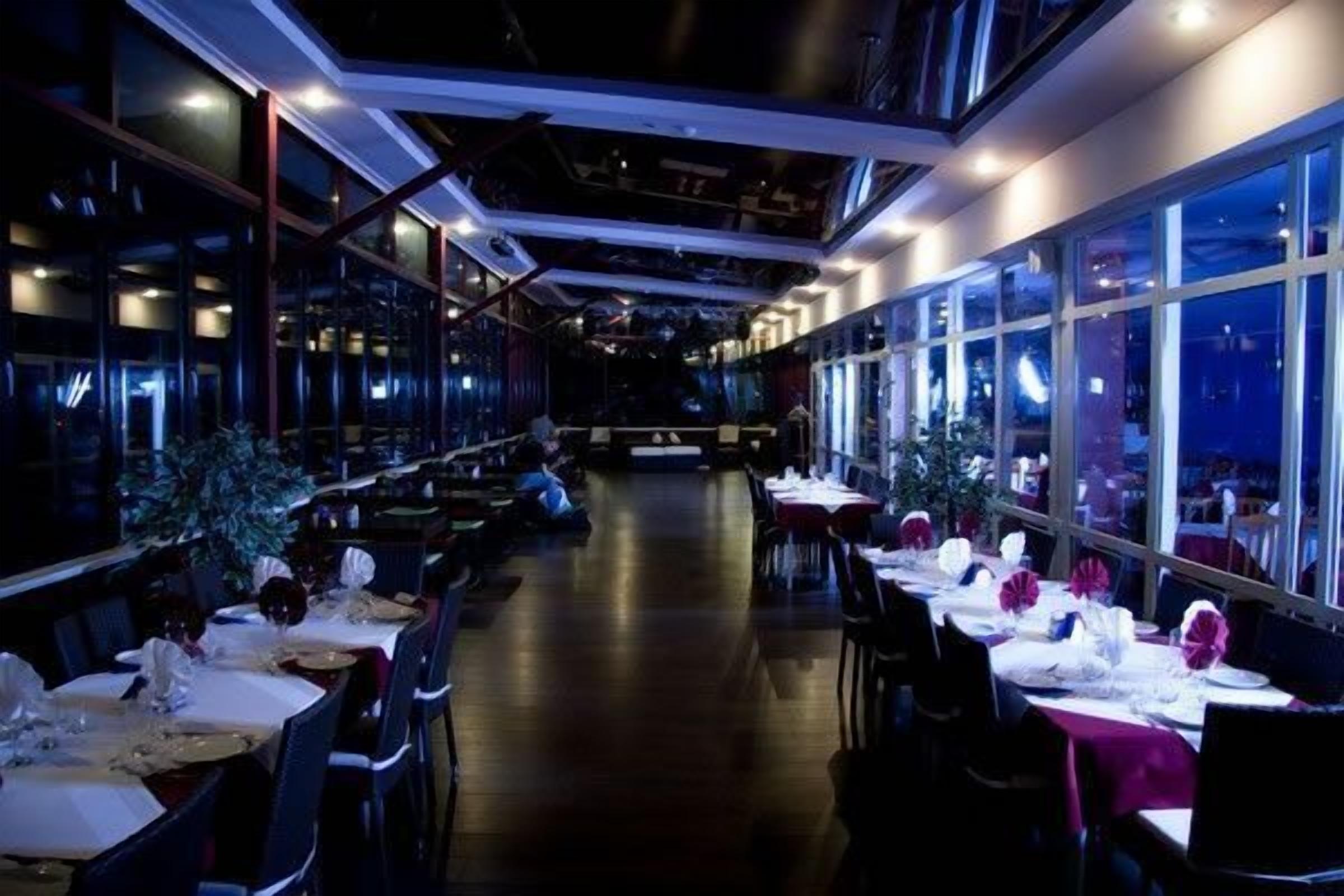 A restaurant with tables set for dining, large windows, and a modern interior design.