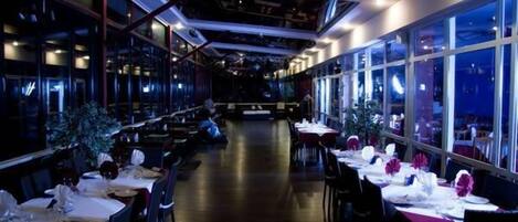Um restaurante com mesas postas, amplas janelas e design de interiores moderno.