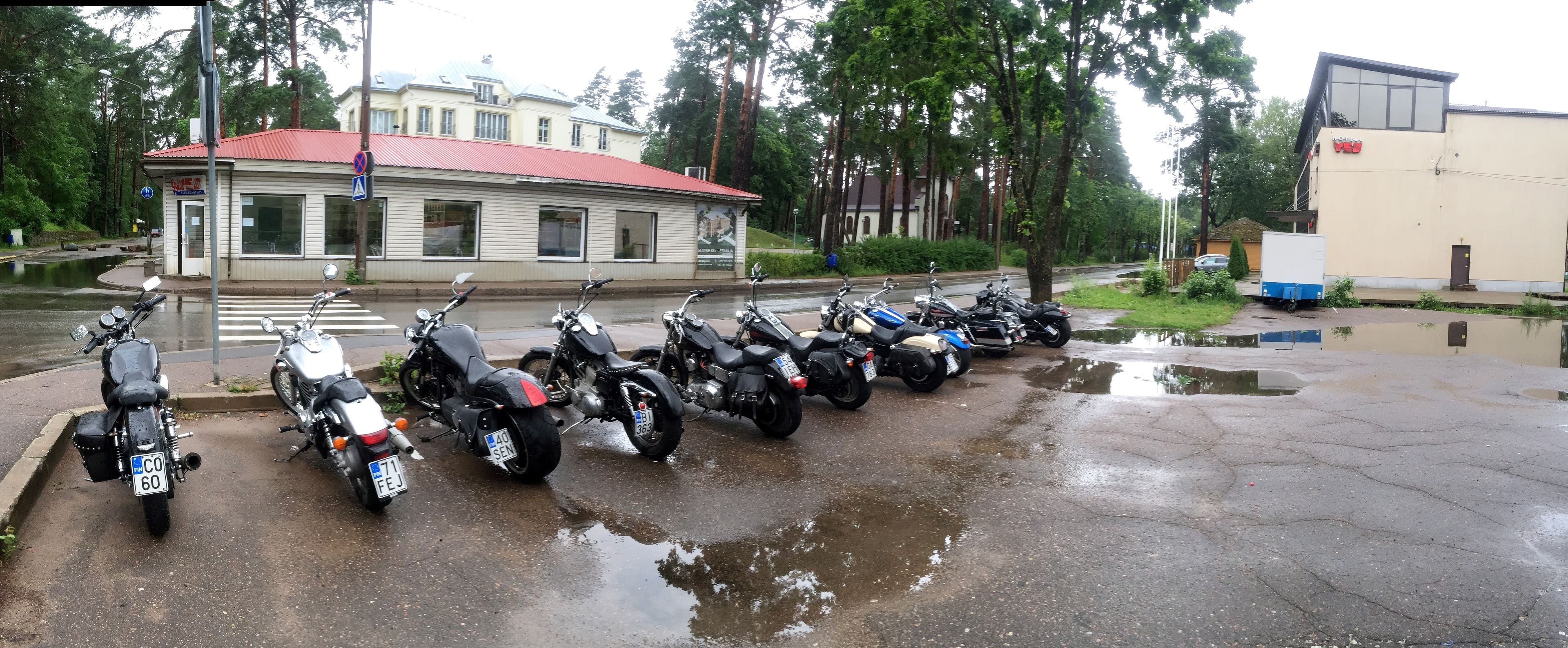 Una fila de motocicletas estacionadas en un estacionamiento, con un edificio al fondo.