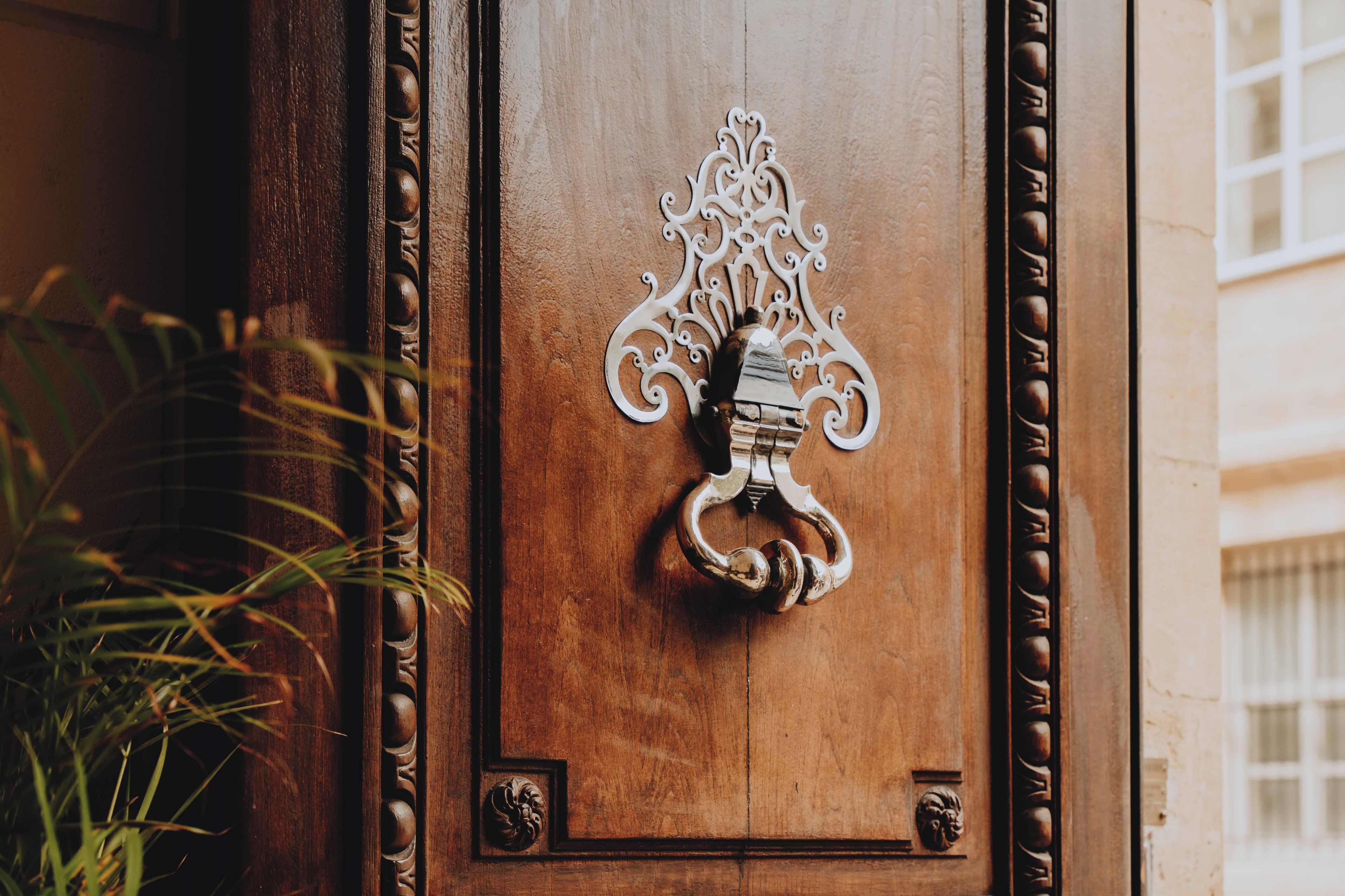 A wooden door with an ornate metal knocker and a decorative handle.