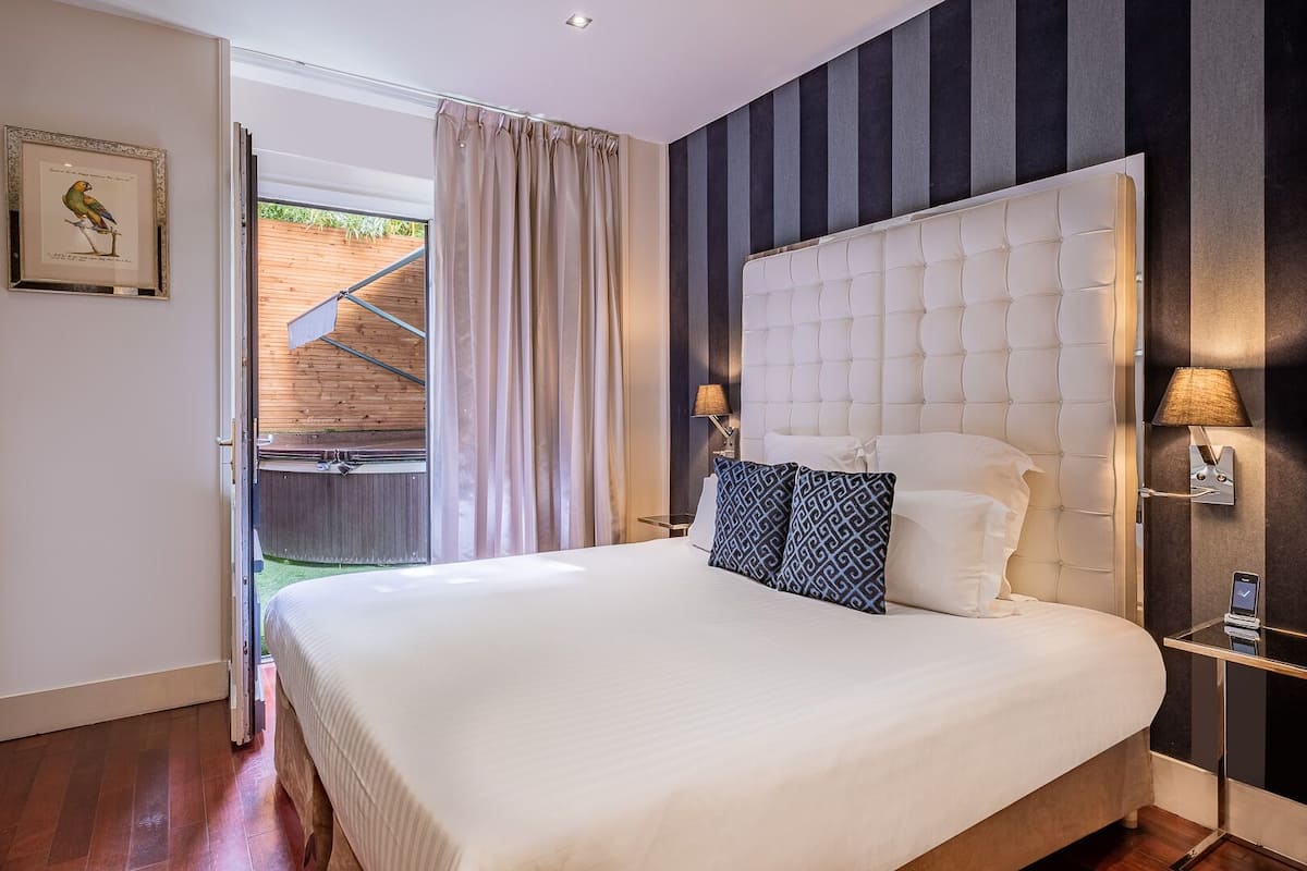 A bedroom with a large bed, a headboard, bedside lamps, and a framed picture on the wall.