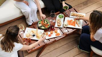 Un grupo de personas sentadas alrededor de una mesa de madera con varios platos, bebidas y una ensalada.
