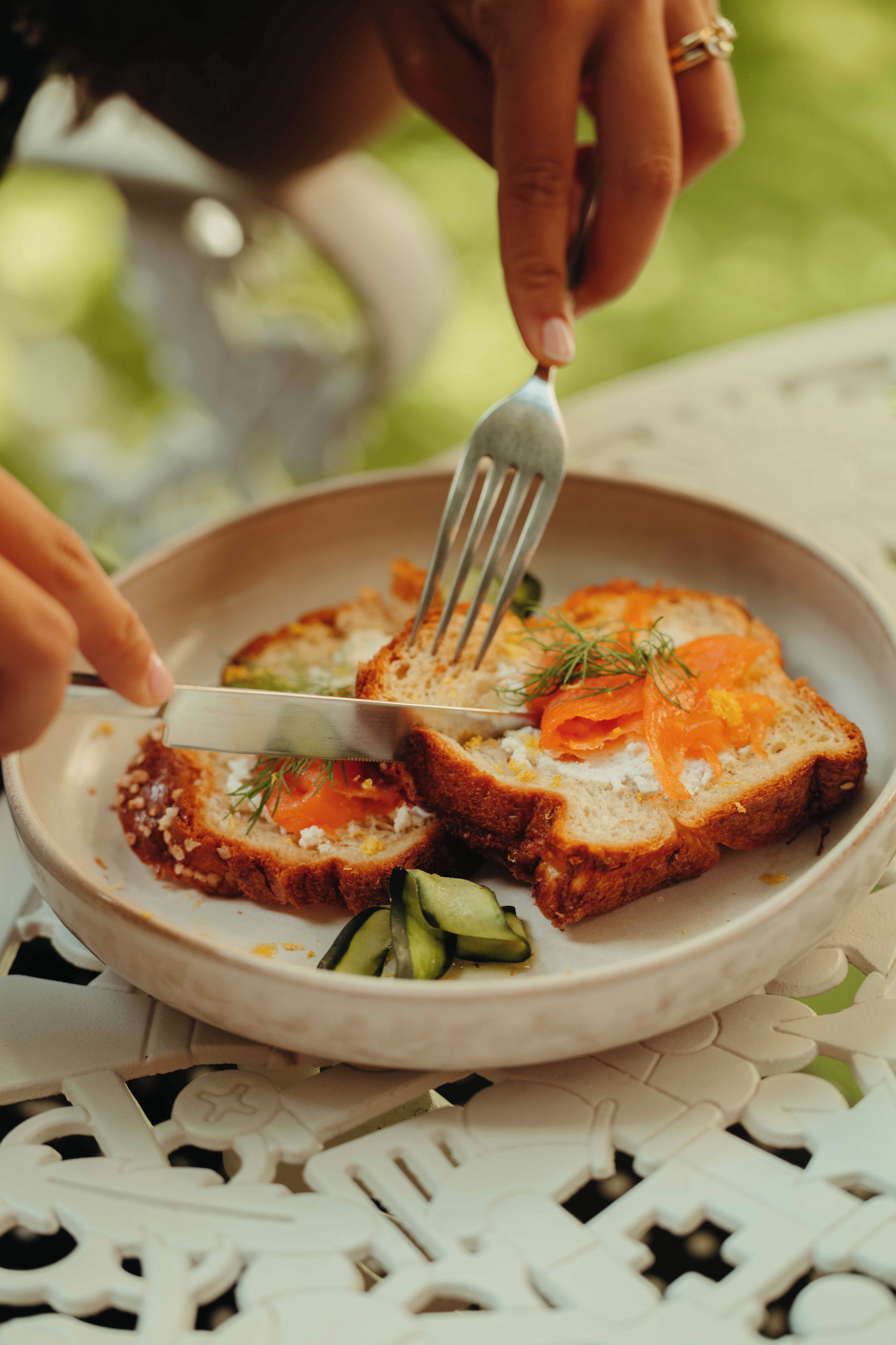 A person cutting a sandwich with a fork on a plate.