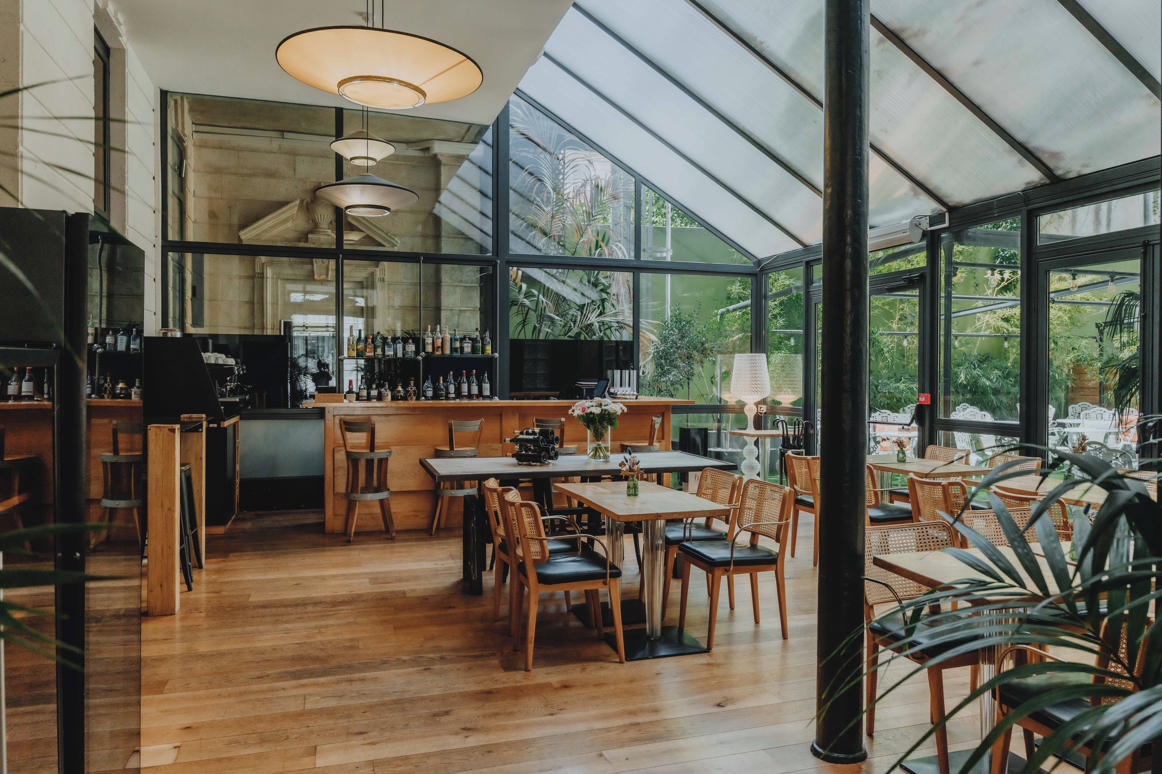 A restaurant with a bar area, wooden tables, and chairs.