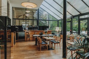 Un restaurante con área de bar, mesas y sillas de madera.