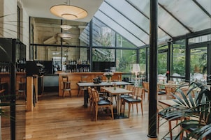 Un ristorante con un'area bar, tavoli e sedie in legno.