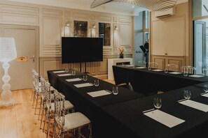 A conference room with a long table, chairs, a television, and a decorative wall piece. - Le Boutique Hotel & Spa (Bordeaux)
