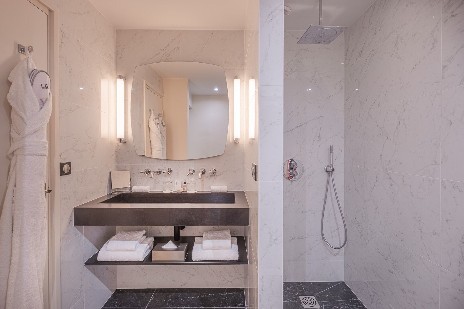 A modern bathroom with a marble sink, a large mirror, and a shower.