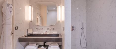 A modern bathroom with a marble sink, a large mirror, and a shower.