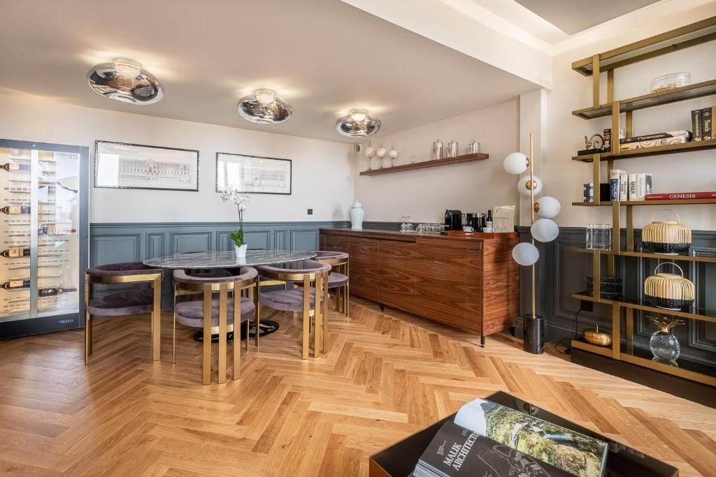 Una cucina moderna con un'isola in legno, lampade a sospensione e una libreria.