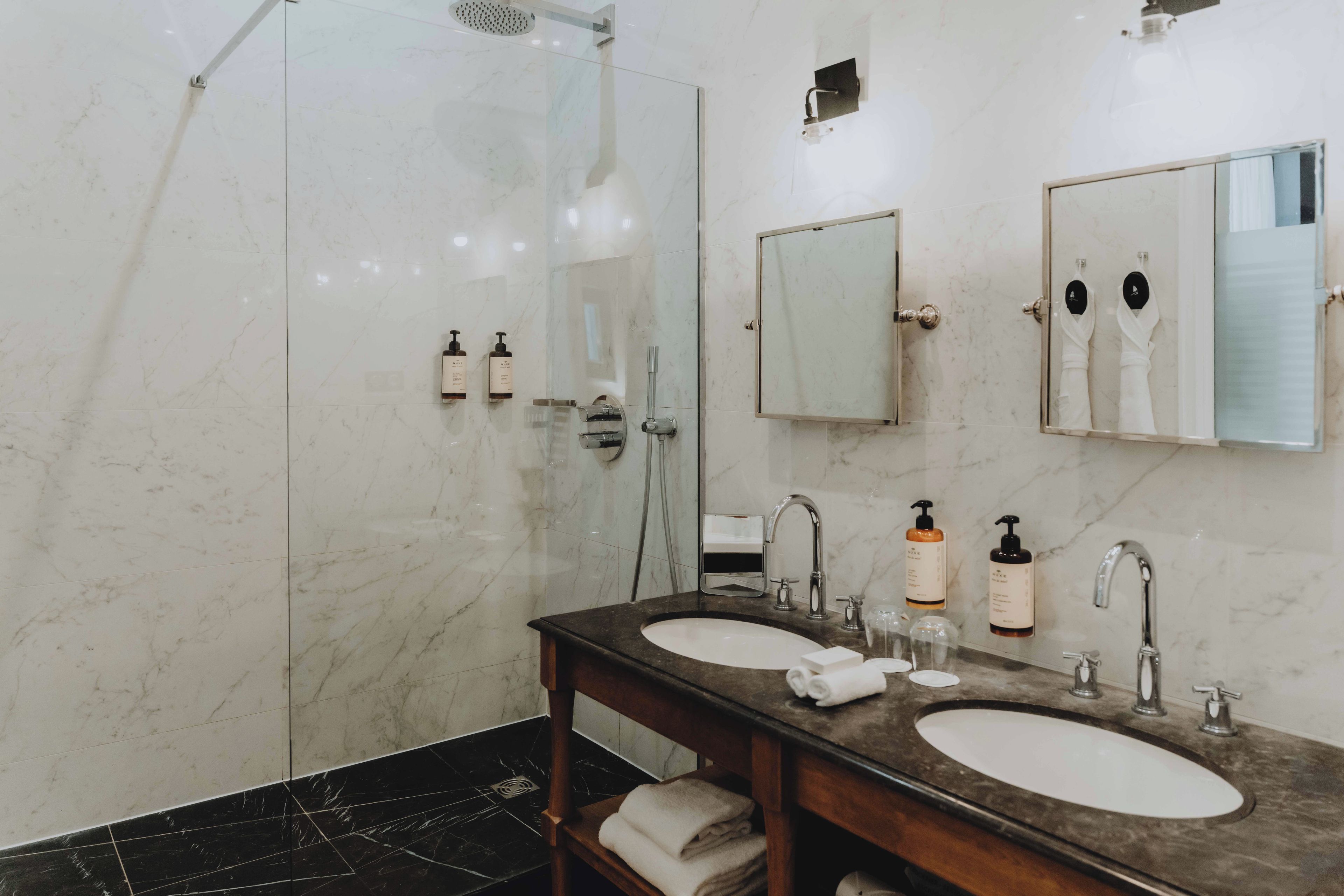 Un baño moderno con dos lavamanos, una ducha y un espejo grande.