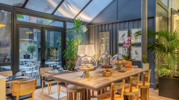 An indoor dining area with a wooden table, chairs, and a glass enclosure displaying food.