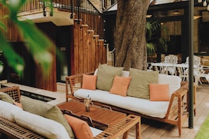 A wooden outdoor seating area with a sofa and chairs, a small table, and a tree. - Le Boutique Hotel & Spa (Bordeaux)