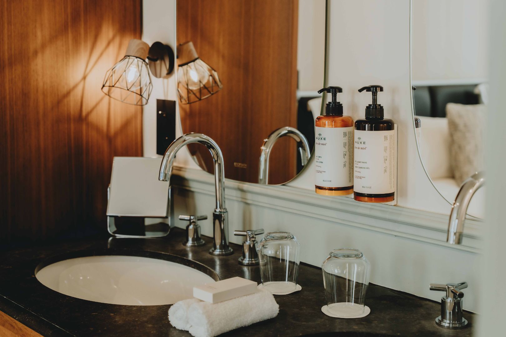 A bathroom with a large mirror, two sinks, a towel, and toiletries.