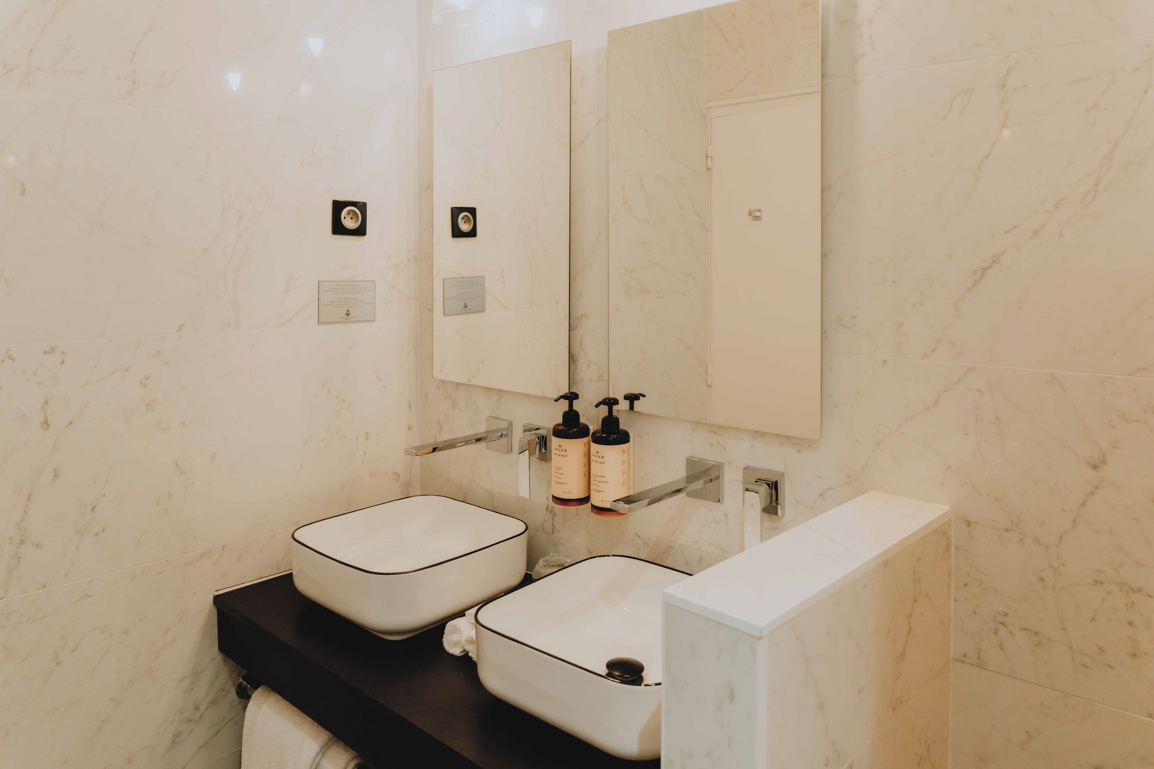 Un baño con dos lavamanos, un espejo y artículos de aseo.