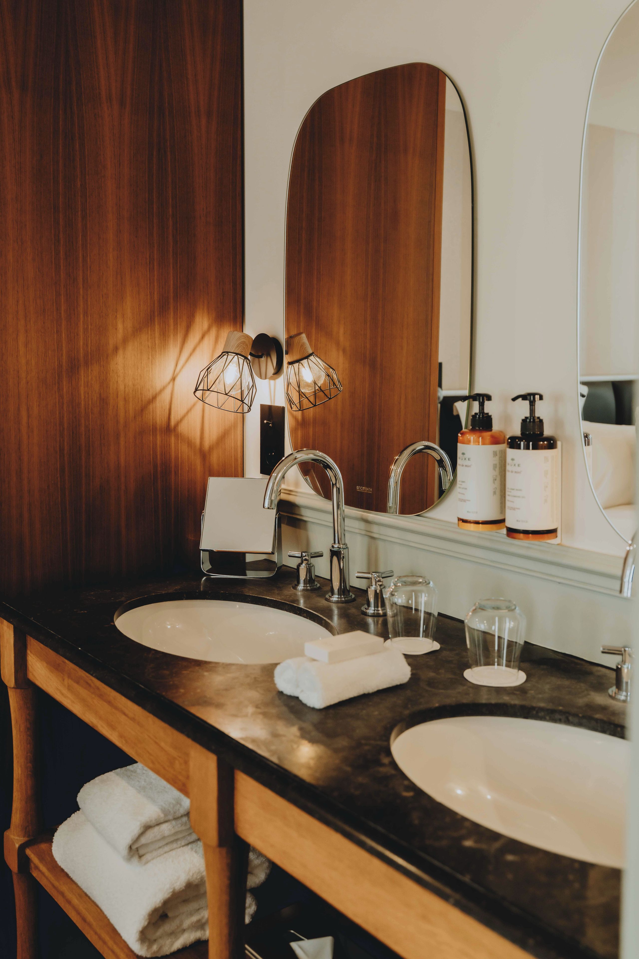 Une salle de bain avec deux lavabos, un miroir et un porte-serviettes.