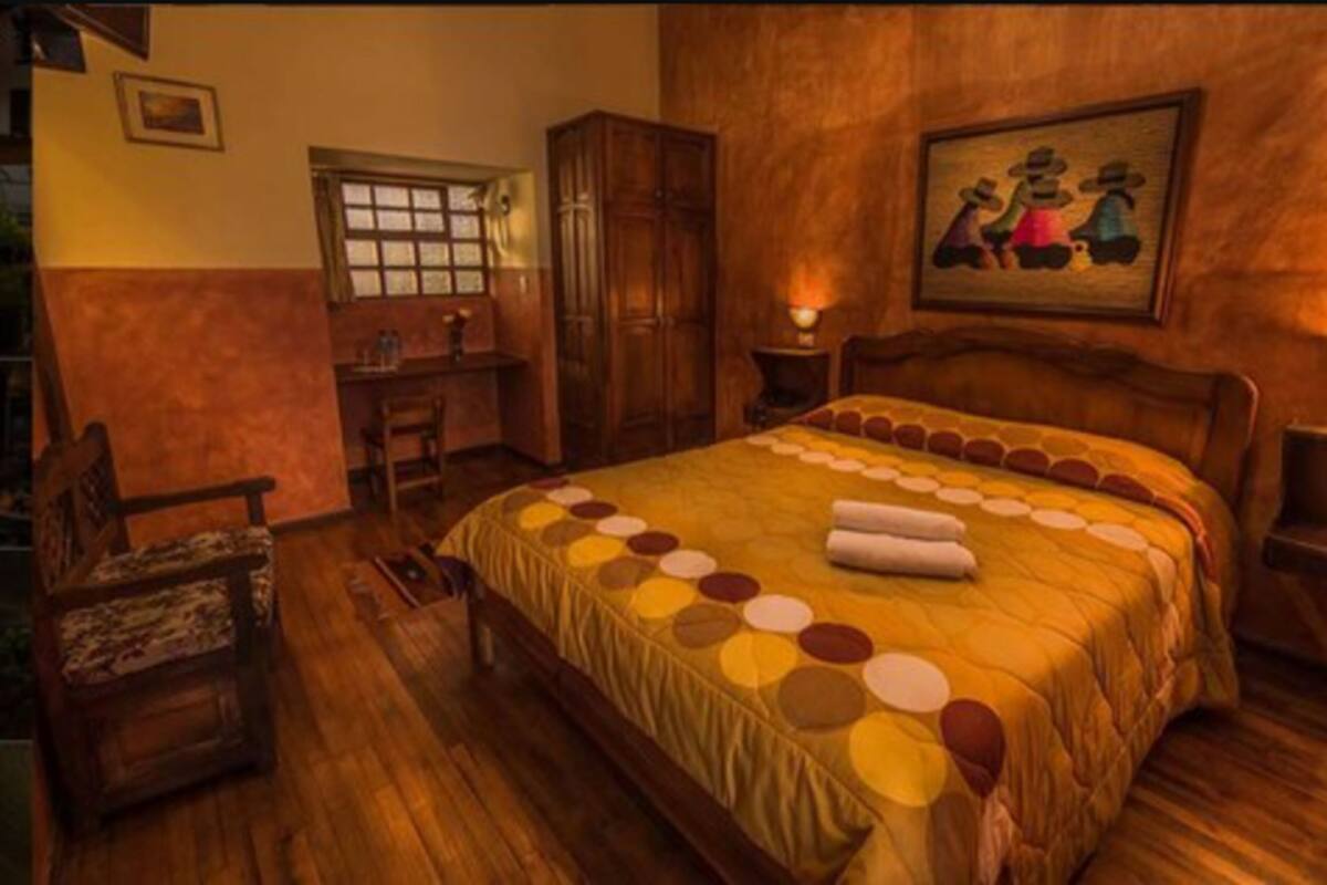 Une chambre avec un grand lit, des meubles en bois, un bureau et un tableau au mur.