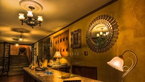 A hotel reception area with a reception desk, a chandelier, a mirror, and a staircase in the background. - Hotel San Francisco de Quito (Quito)