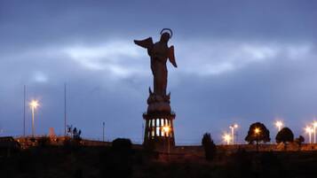 Una estatua en un parque al anochecer con farolas al fondo.