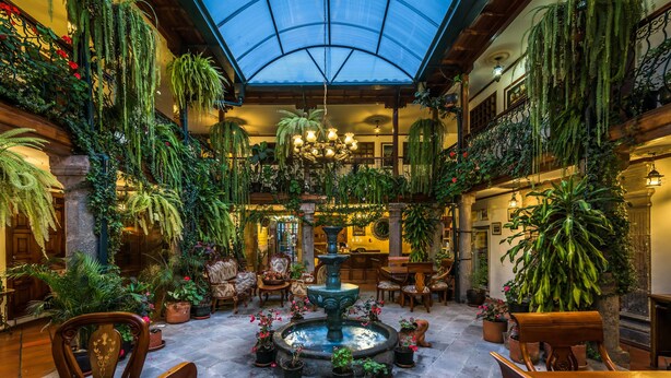 A spacious atrium with a central fountain, surrounded by lush greenery and wooden furniture. - Hotel San Francisco de Quito (Quito)