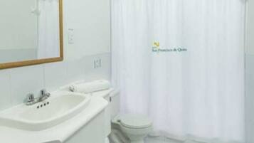 Un baño moderno con lavamanos, espejo y inodoro blancos.