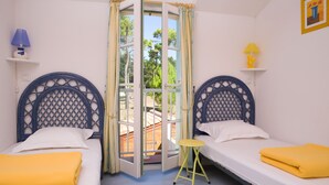 A room with two beds, a small stool, and a door leading outside. - Madame Vacances Les Mas de St Hilaire (Saint-Hilaire-de-Riez)