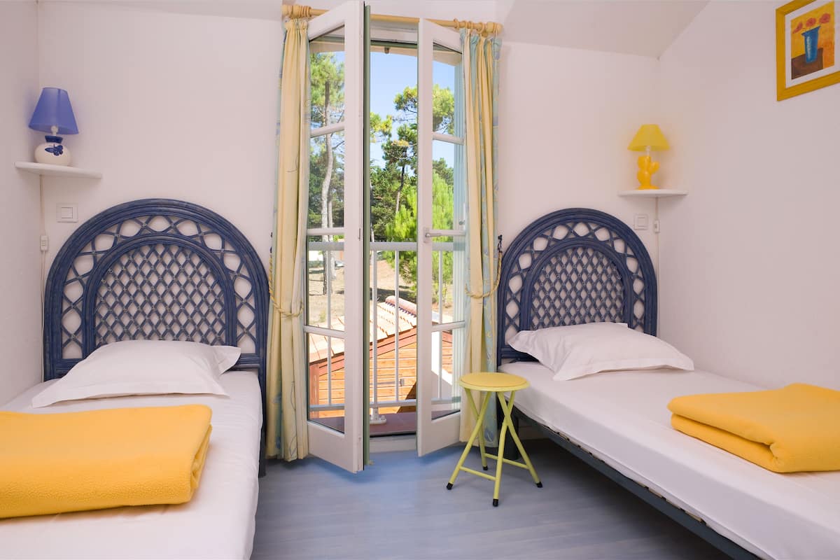 A room with two beds, a small stool, and a door leading outside.