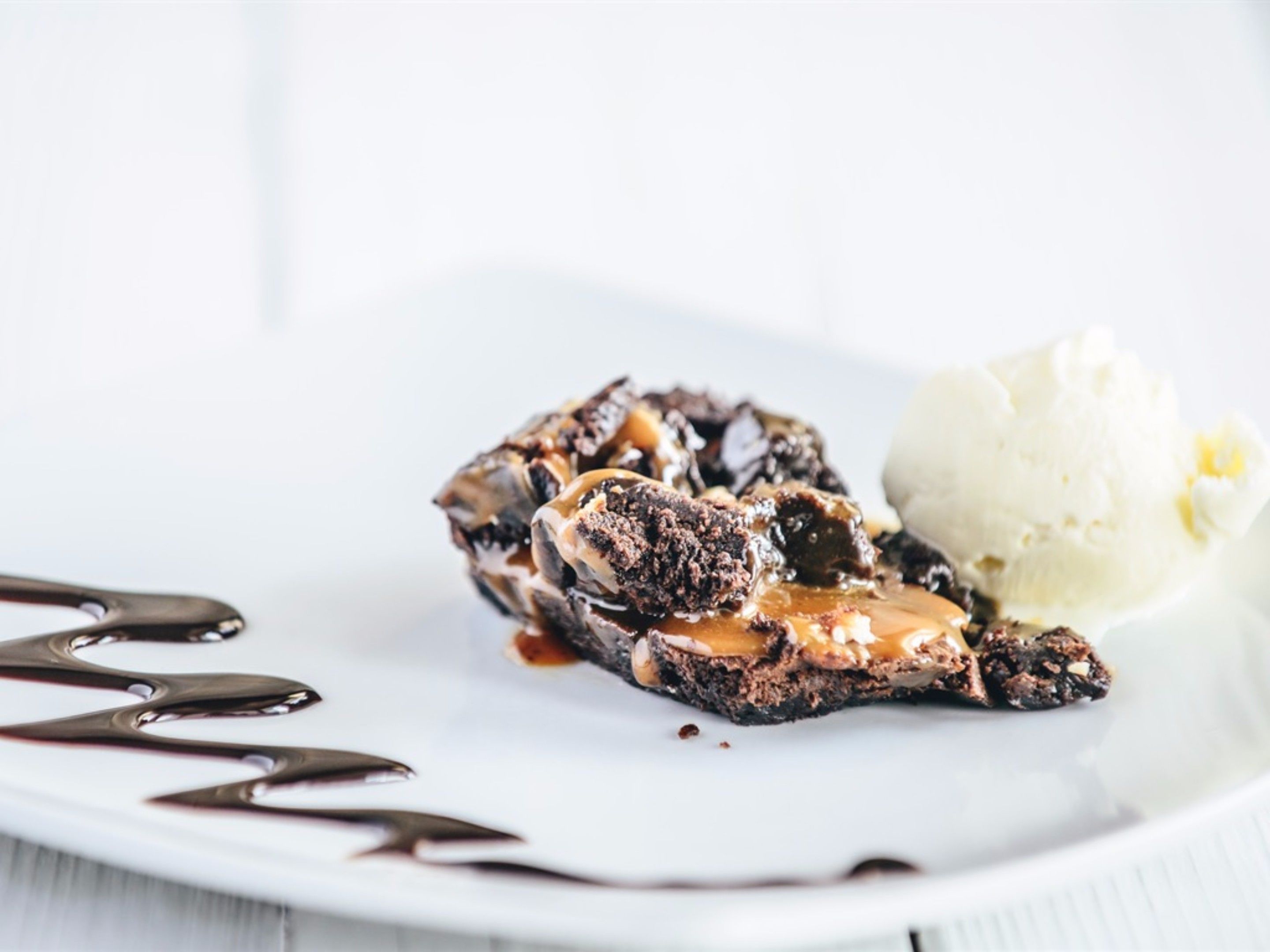 A dessert plate with a chocolate lava cake, caramel sauce, and a scoop of vanilla ice cream.