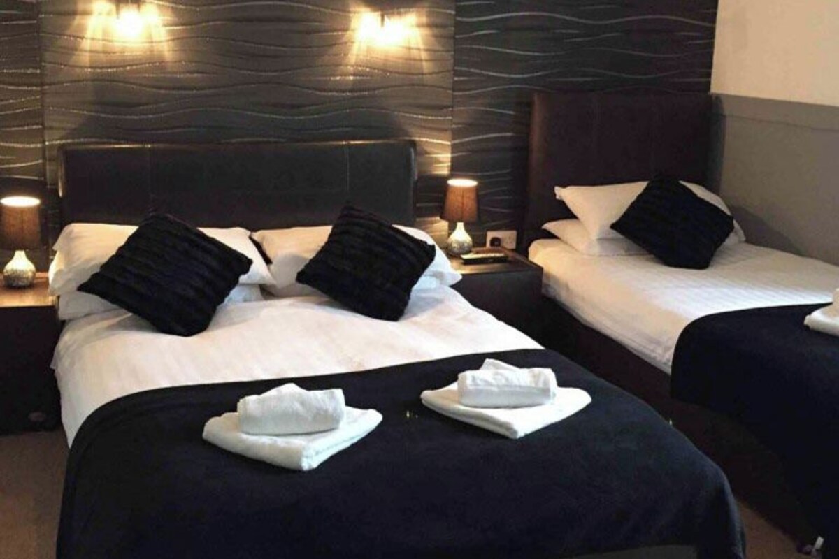 A hotel room with two beds, dark headboards, and bedside lamps.