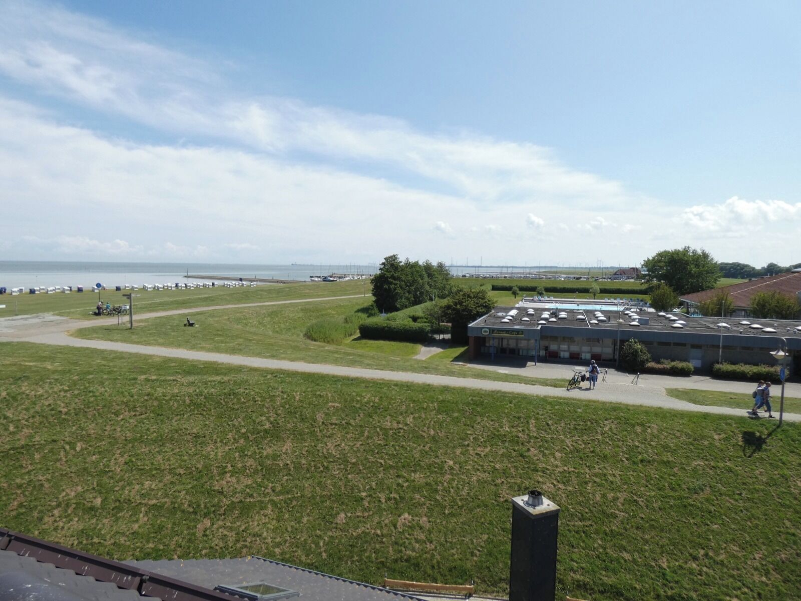 Une zone herbeuse avec un bâtiment, un chemin et une vue sur la mer.