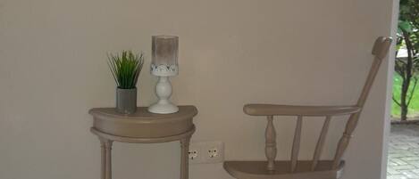 A wall with a 'WELCOME' sign, a small table with a plant, and a wooden chair.