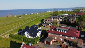 A residential area with houses, a grassy field, and a marina with boats. - Hotel Arche Noah (Wangerland)