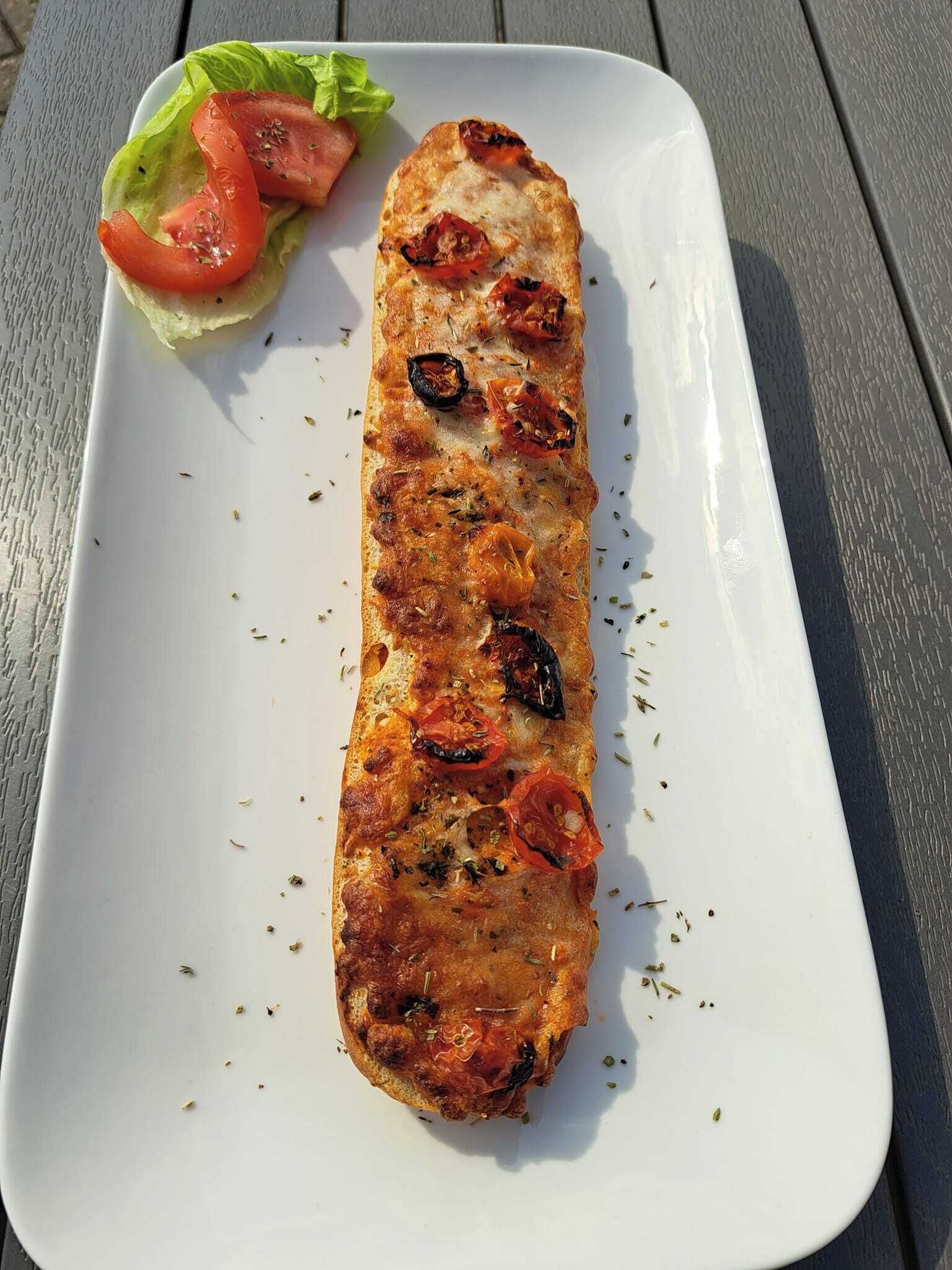 A grilled fish fillet on a white plate with a side salad of lettuce and tomatoes.