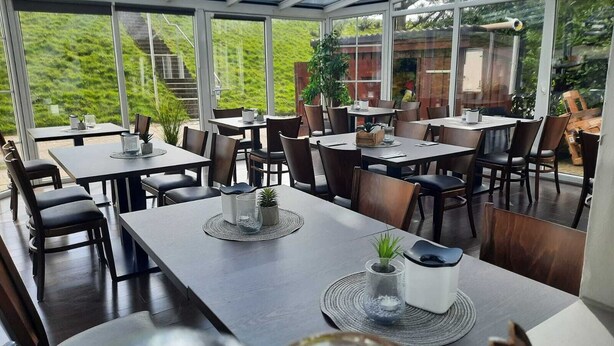 A restaurant with a glass ceiling, outdoor seating, and a view of a green landscape. - Hotel Arche Noah (Wangerland)