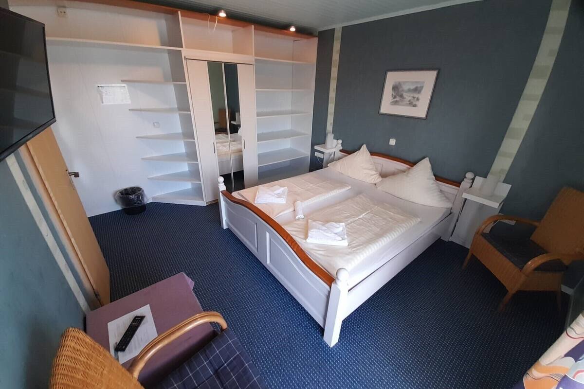 A hotel room with a bed, a wardrobe, a desk, and a chair.