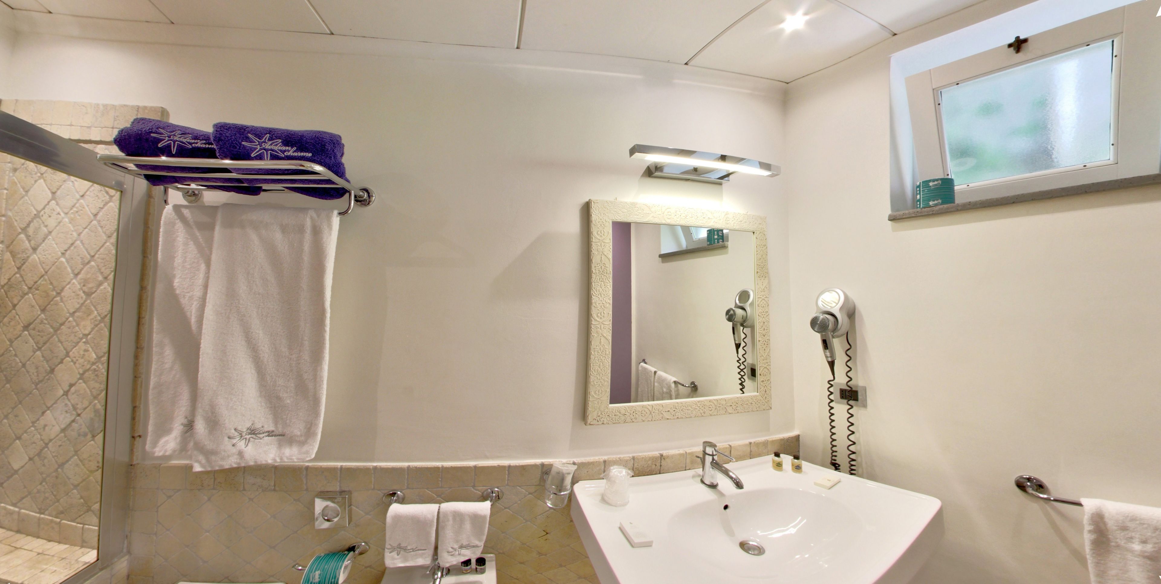 A bathroom with a sink, mirror, towel rack, and a hairdryer.