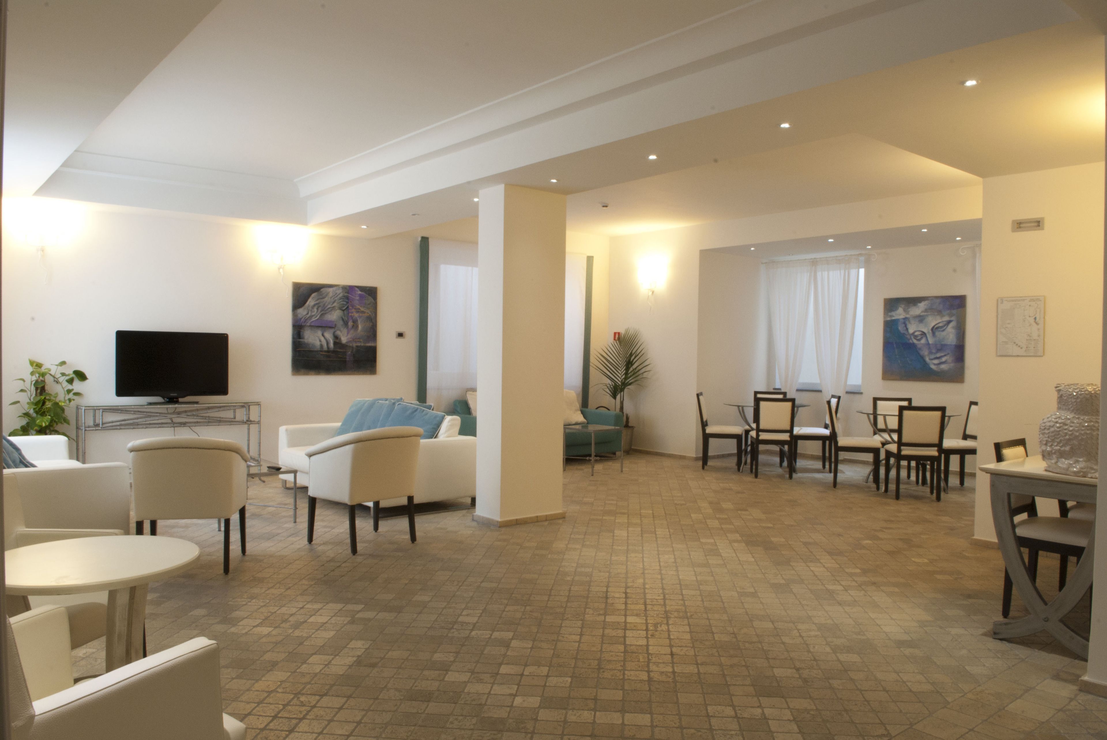 A spacious living area with a flat-screen TV, comfortable seating, and a dining area with chairs and a table.