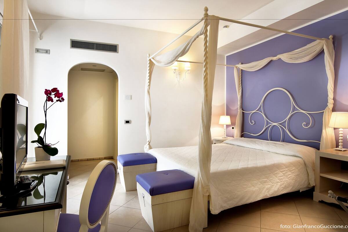 Ein Schlafzimmer mit einem Himmelbett, einem Schreibtisch mit Stuhl und einer Wand in Lila.