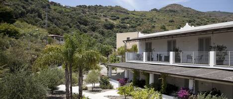 A building with a balcony overlooking a landscaped garden with various plants and a pathway.