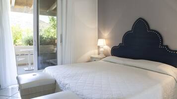A bedroom with a bed, a nightstand, a lamp, and a view of an outdoor area with a table and chairs.