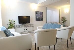 Una sala de estar moderna con un televisor de pantalla plana, sofás blancos y un cuadro grande en la pared.