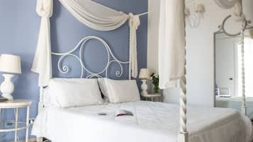 Un dormitorio con cama con dosel, una mesita de noche con lámpara y un espejo en la pared.