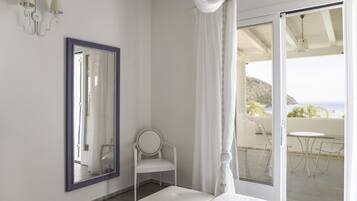 Une chambre dotée d’un grand miroir, d’une chaise, d’un lit et d’un balcon aménagé avec du mobilier d’extérieur.