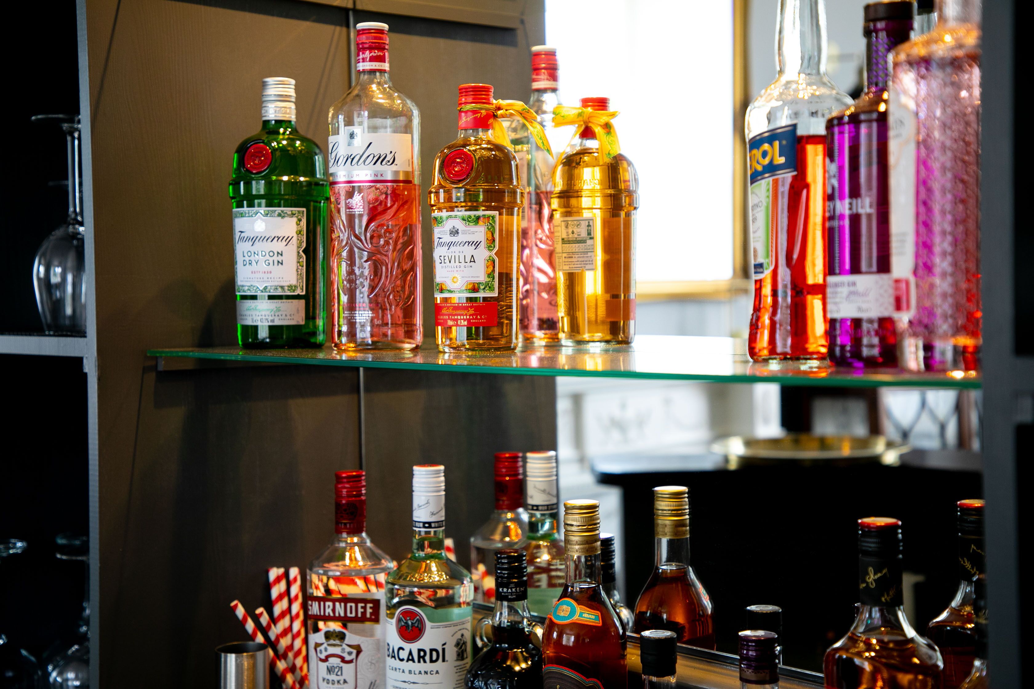A variety of liquor bottles on shelves in a bar setting.