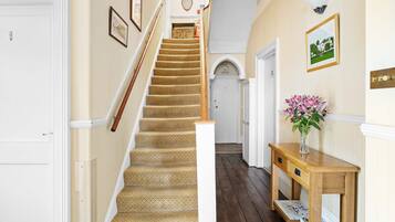 A staircase with patterned carpet, a wooden handrail, and a white door at the top.