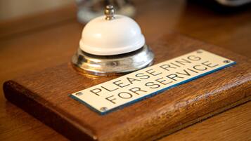 A wooden reception desk with a sign that reads "PLEASE RING FOR SERVICE."