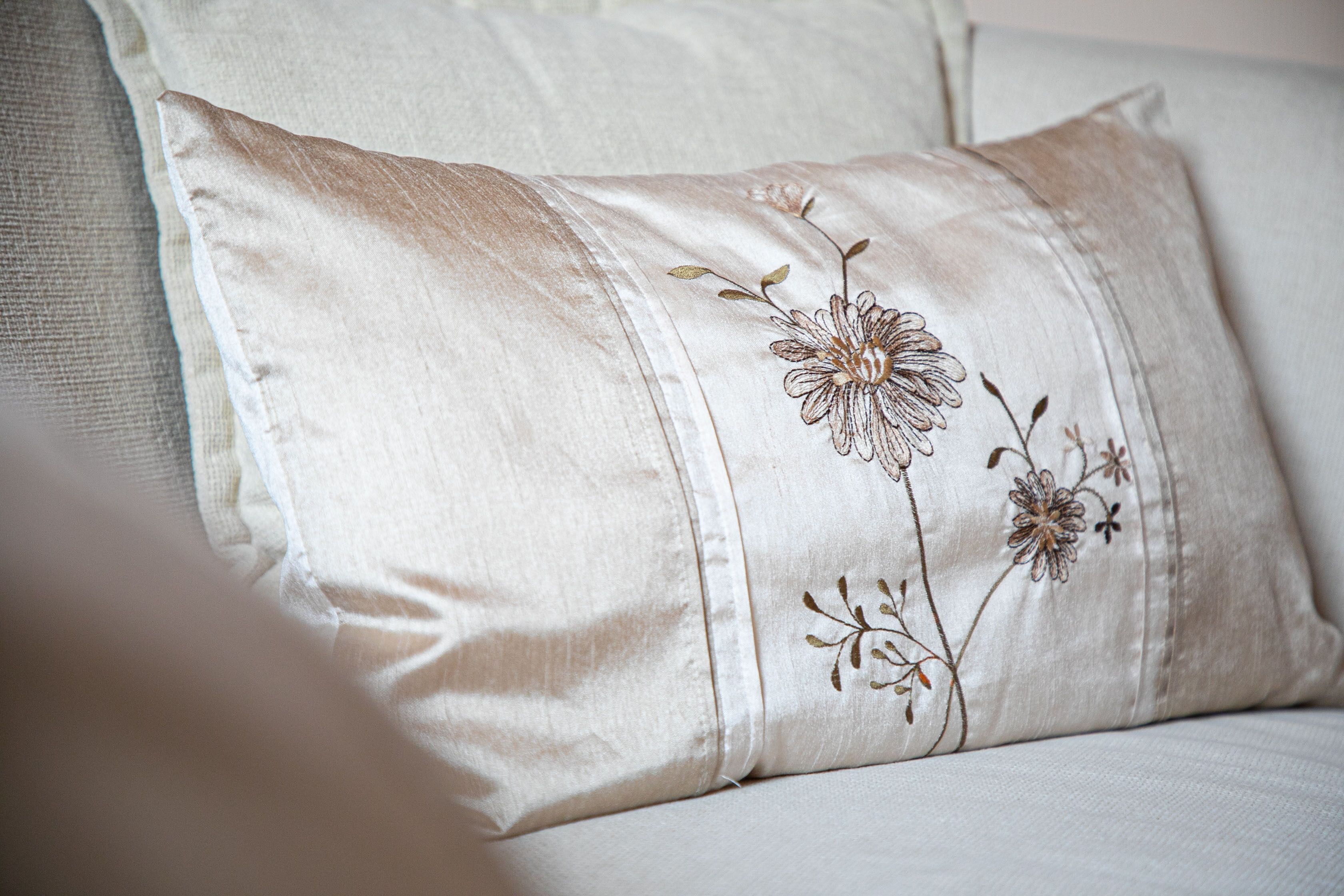 A close-up of a pillow with floral embroidery on a white sofa.