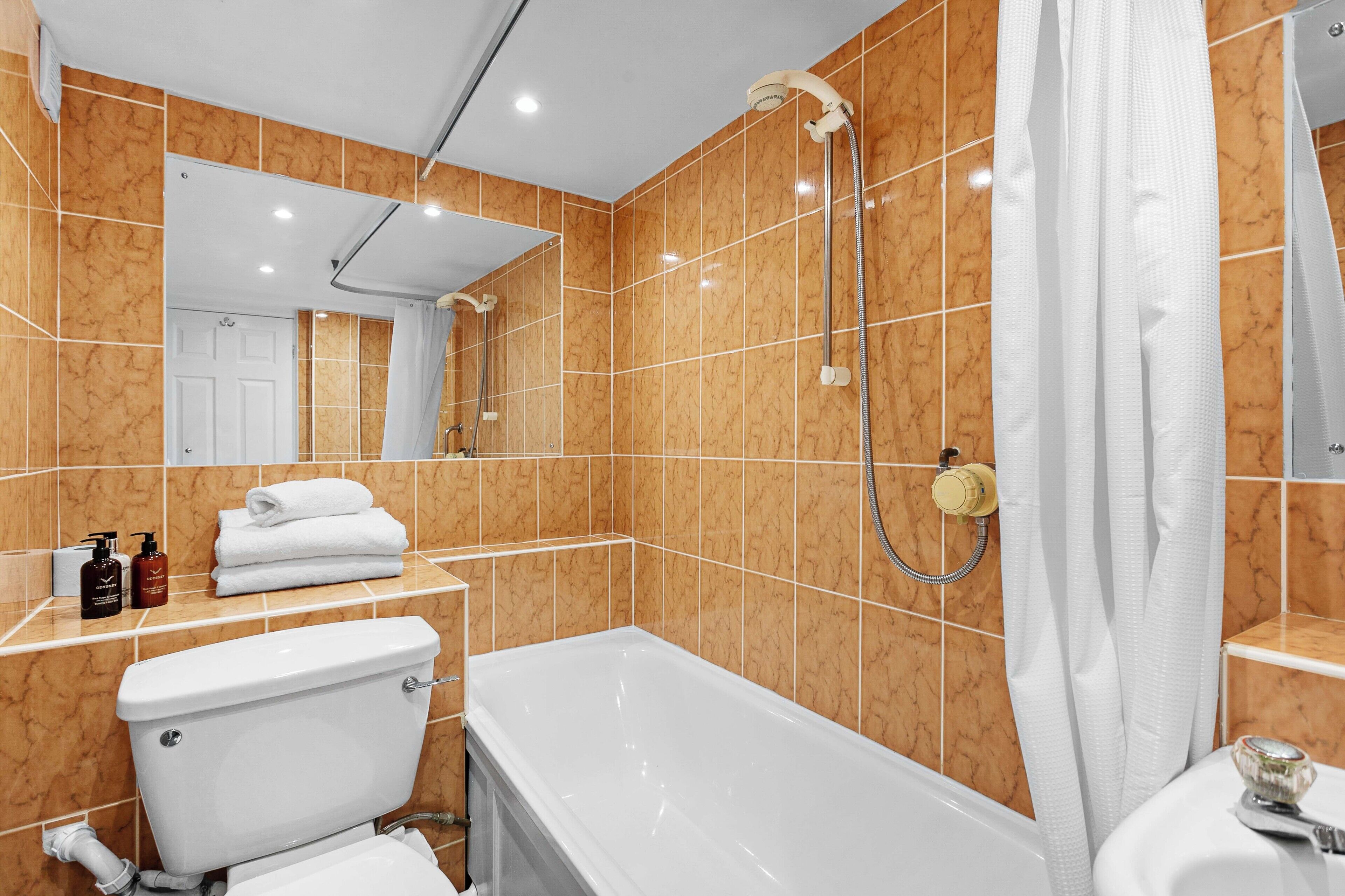 Een badkamer met een wit toilet, een badkuip en een douche met een handdouche.